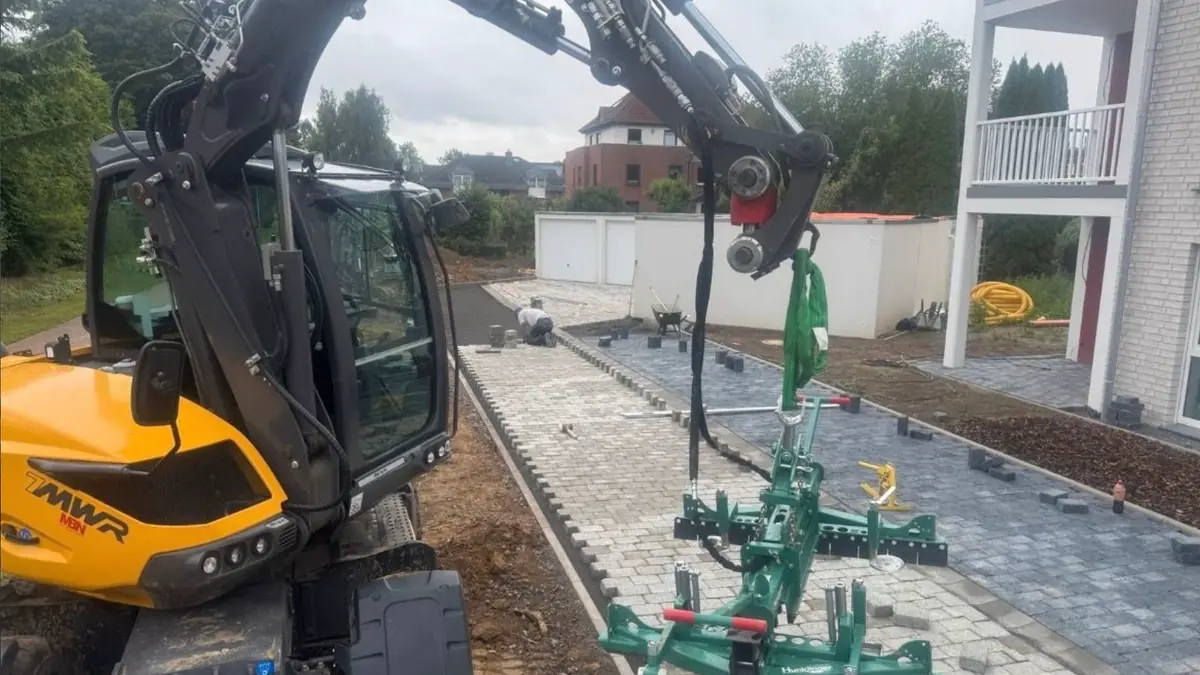 Mobilbagger von A.D. Bau mit Verlegezange auf einer Pflasterbaustelle