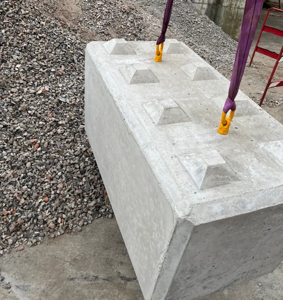 Betonfertigteil hängt am Hebegeschirr über dem Lagerplatz
